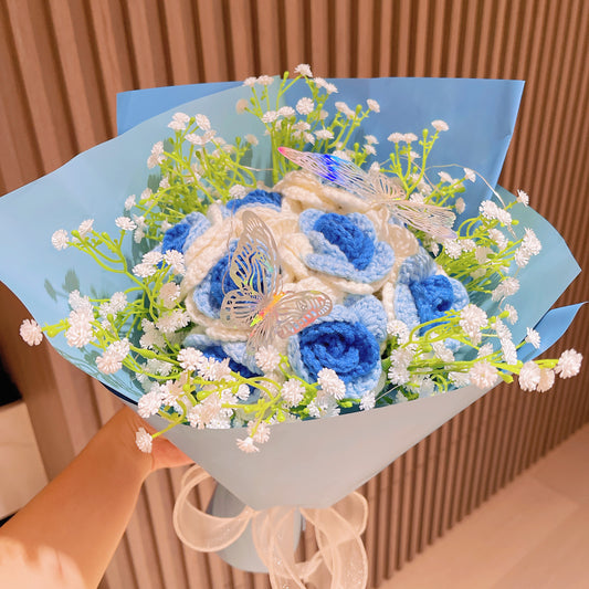 Bouquet de roses glacées dégradées du blanc au bleu avec du souffle de bébé blanc et des accents de papillons aux couleurs vives, joliment enveloppé dans des papiers bleu clair et bleu foncé, idéal pour les célébrations de type princesse