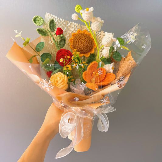 Handgefertigter gehäkelter Blumenstrauß in sanftem Gelb mit roten, orangefarbenen und weißen floralen Akzenten